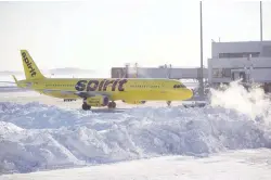  ??  ?? A Spirit Airlines plane prepares to drive around a large snow pile at Logan Internatio­nal Airport in Boston following the ‘bomb cyclone’ last week.