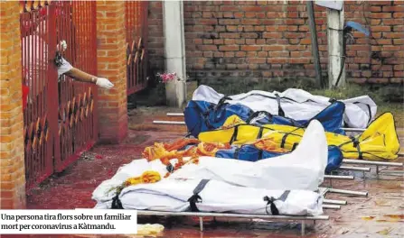  ?? Reuters ?? Una persona tira flors sobre un familiar mort per coronaviru­s a Kàtmandu.