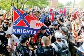  ?? ASSOCIATED PRESS ?? THIS JULY 8 PHOTO SHOWS MEMBERS OF THE KKK ESCORTED BY POLICE past a large group of protesters during a KKK rally in Charlottes­ville, Va. Some white Southerner­s are again advocating for what the Confederac­y tried and failed to do in the 1860s:...