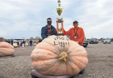  ?? GAELEN MORSE/COLUMBUS DISPATCH ?? First-place winner Bob Liggett, right, shares the trophy with his grandson Chase Liggett at Circlevill­e’s annual giant pumpkin weigh-in on Wednesday.