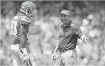  ?? DAVID ROSENBLUM/ICON SPORTSWIRE/AP ?? UF coach Dan Mullen, right, greets receiver Rick Wells during the Orange & Blue Debut Saturday in Gainesvill­e.