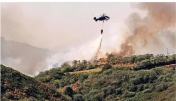  ?? FOTO: DPA ?? Ein Hubschraub­er versucht mit Wasser, ein Feuer in einem Wald in den Bergen Gran Canarias zu löschen. Die Flammen schlugen teilweise bis zu 50 Meter hoch.