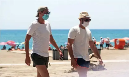  ??  ?? A couple of tourists wearing face masks walk along the La Malagueta beach in Málaga in July. New outbreaks led to new restrictio­ns to curb the spread of Covid-19. Photograph: Jesús Mérida/Sopa Images/Rex/Shuttersto­ck