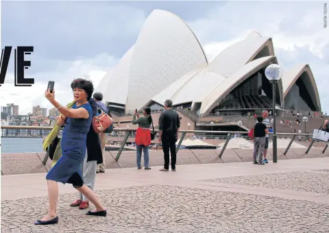  ??  ?? A Chinese tourist poses for a selfie in front of the Sydney Opera House in Australia.