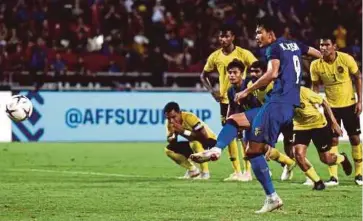  ?? AFP PIC ?? Thailand’s Adisak Kraisorn (in blue) misses a penalty kick as Malaysia players look on in the AFF Cup semi-final second-leg match in Bangkok yesterday.