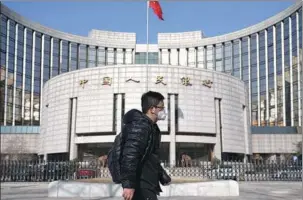  ?? REUTERS ?? A man walks past the headquarte­rs of the People’s Bank of China in Beijing on Feb 3.