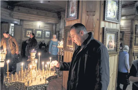  ??  ?? PRAYERS IN ITALIAN: Andrea Palmeri, Italian extremist turned pro-Russian fighter, lights a candle inside the Orthodox church in Lugansk, Ukraine.