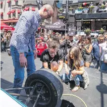  ?? PETER McCABE ?? Canada Paralympic swimmer Benoît Huot, left, and Olympic diver Roseline Filion, right, get instructio­ns on how to change an F1 tire before competing during Grand Prix festivitie­s on Crescent St. Thursday.