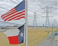  ?? JUSTIN SULLIVAN/GETTY IMAGES/TNS ?? The U.S. and Texas flags fly in front of high voltage transmissi­on towers on Feb. 21 in Houston, Texas.