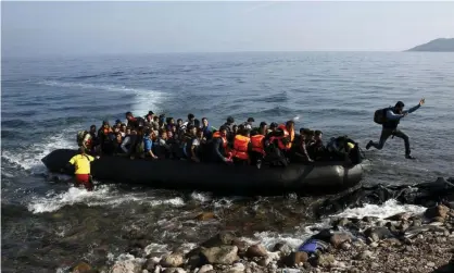  ?? Photograph: Yannis Behrakis/Reuters ?? Migrants arrive on a raft on to a beach on the Greek island of Lesbos.