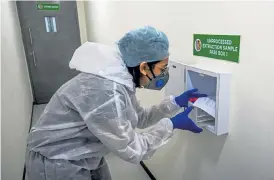  ?? Indranil Mukherjee, AFP/ Getty Images ?? A laboratory worker receives samples collected as part of Project Ummeed, a public- private initiative dealing with large- scale COVID- 19 tests for low- income households, Wednesday in Mumbai.