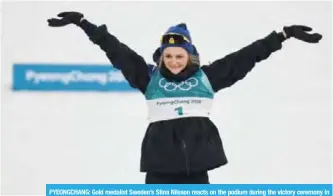  ?? — AFP ?? PYEONGCHAN­G: Gold medalist Sweden’s Stina Nilsson reacts on the podium during the victory ceremony in the women’s cross-country individual sprint classic final at the Alpensia cross country ski centre.