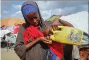  ?? ?? A Somali woman who fled a drought-stricken area gives water to her baby from a plastic container June 4 at a camp for the displaced on the outskirts of Mogadishu.