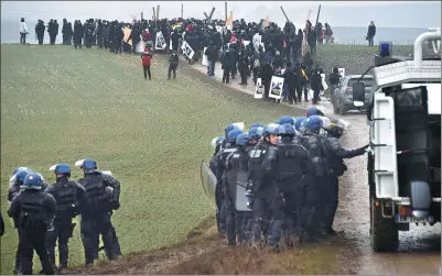  ?? JEAN-CHRISTOPHE VERHAEGEN / AGENCE FRANCE-PRESSE ?? Riot police officers patrol next to a group of anti-nuclear activists as they walk toward Lejuc Wood in Mandres-en-Barrois, eastern France, on Saturday.