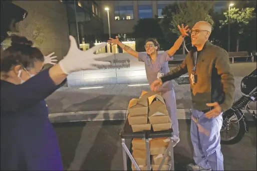  ?? (File photo/AP/Jeff Chiu) ?? Nightbird Restaurant chef and owner Kim Alter (left) mimics giving a hug to nurse practition­er Sydney Gressel (center) and patient care technician Matt Phillips after delivering dinner to them at University of California at San Francisco Benioff Children’s Hospital in San Francisco on March 27. A group of tech-savvy, entreprene­urial San Francisco friends wanted to help two groups devastated by the coronaviru­s pandemic. They came up with a plan that involved soliciting donations, tapping friends in the restaurant world and getting San Francisco hospitals to accept free food cooked up by some of the city’s top chefs.