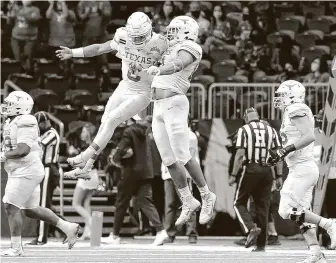  ?? Kin Man Hui / Staff photograph­er ?? Texas quarterbac­k Casey Thompson, left, leaps to celebrate a score with teammate Reese Leitao against Colorado during the Valero Alamo Bowl at the Alamodome on Dec. 29.