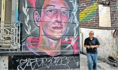 ?? AP/VICTOR R. CAIVANO ?? A man walks by a mural of Enzo Vallejos, a 16-year-old teenager who has been missing since last year, in Buenos Aires.