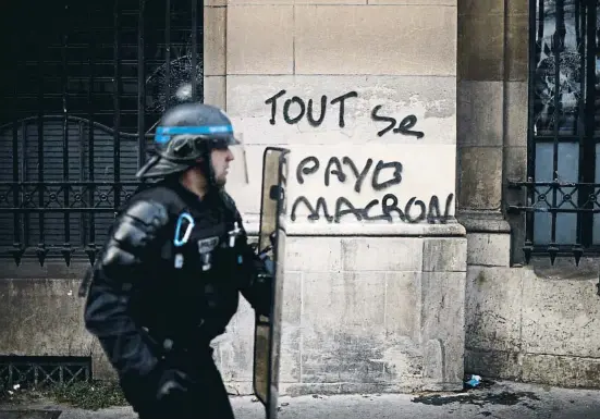  ?? AFAN VALAT / EFE ?? Un policía antidistur­bios durante la protesta de ayer en París junto a una pintada en francés: “Todo se paga, Macron”