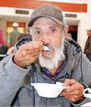  ??  ?? A man who gave his name as Torres enjoys hot food provided by members of St. Andrew Catholic Church’s Rother Men’s group.