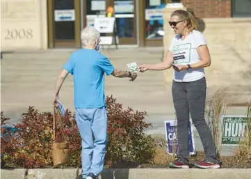  ?? STACEY WESCOTT/CHICAGO TRIBUNE ?? Lorri Grainawi stands outside the Arlington Heights Village Hall on Thursday and hands informatio­n to early voters about a referendum to create a tax levy for a mental health board.