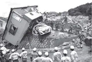  ?? SADAYUKI GOTO/KYODO NEWS VIA AP ?? Rescuers search for missing persons in Kumano town, Hiroshima prefecture, western Japan on Monday. People prepared for risky search and cleanup efforts in southweste­rn Japan on Monday, where several days of heavy rainfall had set off flooding and...