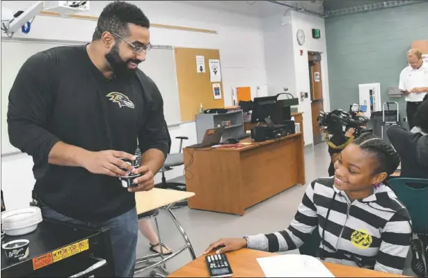  ?? (File Photo/AP/Steve Ruark) ?? John Urschel (left), a math scholar and former Baltimore Ravens lineman, hands out ice cream to Chelsy Valerio, 14, of Baltimore during a lesson at Dundalk High School during the launch of Texas Instrument­s’ STEM Behind Cool Careers series in Baltimore in July 2017.