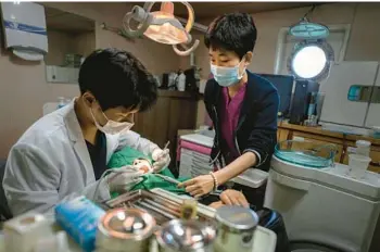  ?? CHANG W. LEE/THE NEW YORK TIMES ?? Lee Gang-min, a dentist, treats Park Meng-sim, 67, on July 20, 2022, aboard the Chungnam 501, a government-run hospital ship that brings free medical services to the residents of remote islands, in Hodo, South Korea.