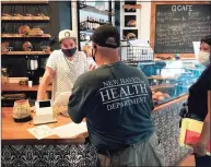  ?? Brian Zahn / Hearst Connecticu­t Media ?? New Haven Senior Sanitarian Brian Mnek shares informatio­n about the city’s mask mandate with G Cafe manager Tyler Demora on Tuesday during a canvass of downtown businesses.