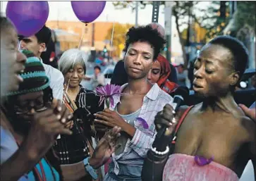  ?? Luis Sinco Los Angeles Times ?? FRIENDS OF Dwayne Fields gather downtown Wednesday, some clutching purple balloons and purple roses in memory of Fields’ love of “Purple Haze.” Among the songs they sang: “Lean on Me” and “Amazing Grace.”
