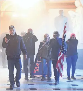  ?? SAUL LOEB/AFP VIA GETTY IMAGES ?? Supporters of President Donald Trump make their way through clouds of tear gas in the corridors of the U.S. Capitol after they broke through police lines and entered the building.