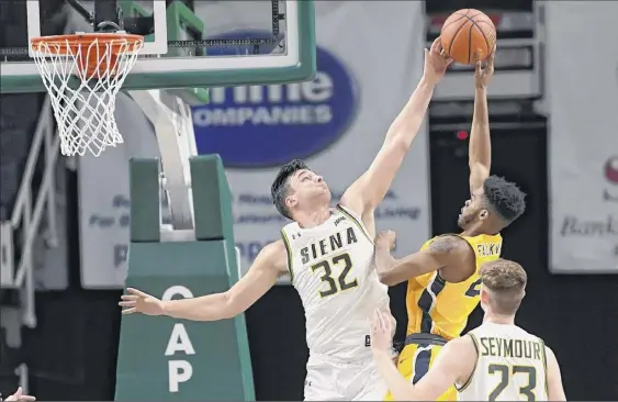  ?? Hans Pennink / Special to the Times Union ?? Siena’s Evan Fisher blocks a shot by Canisius’ Jibreel Faulkner on Saturday. Fisher had 21 points and 17 rebounds for the Saints against the Griffins.