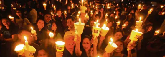  ?? ANDREW TADALAN ?? MAKATI Hundreds of people light up candles at the Makati Ayala Triangle Gardens.