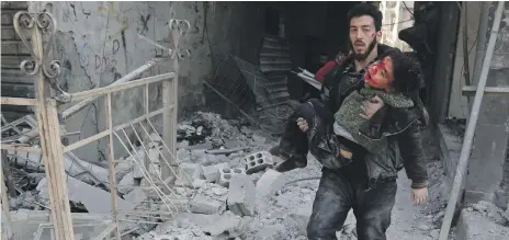  ?? AFP ?? Members of a Syrian civil defence team rescue a child after a regime air strike in Hamouria, Eastern Ghouta