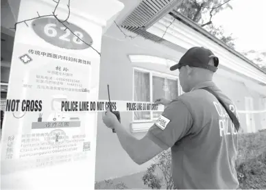  ??  ?? LOCKDOWN — A security officer of Clark Developmen­t Corporatio­n puts a police line across the entrance of one of the villas of the Fontana Resort and Convention Center at the Clark Freeport in Mabalacat City Wednesday, May 20. The leisure park was closed after a treatment facility for the coronaviru­s disease 2019 (COVID-19) was discovered in one of its villas. (Photo courtesy of CDC)