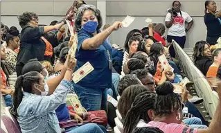  ?? CASSIDY ALEXANDER/CASSIDY.ALEXANDER@AJC.COM ?? Employees of DeKalb County Schools celebrate the early distributi­on of retention bonuses Friday at the district office in Stone Mountain. The bonuses were represente­d by “$2,000 bills,” representi­ng the real money that was directly deposited to their accounts.