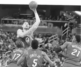  ?? STEPHEN M. DOWELL/ORLANDO SENTINEL ?? Magic center Nikola Vucevic shoots over Miami Heat defenders Rodney McGruder, from left, Derrick Jones Jr. and Hassan Whiteside earlier this year. Vucevic been a key spark for Orlando so far this season.