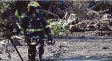  ??  ?? A member of the Orange County Fire Department looking for survivors in Montecito on Wednesday.