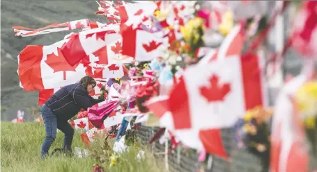  ?? JEFF BASSETT/THE CANADIAN PRESS ?? Jennifer Mcelory of Kamloops places a memorial on the Kamloops Airport fence Thursday. Snowbirds member Capt. Jennifer Casey died when the Snowbirds jet she was in crashed last Sunday. The pilot of the jet suffered serious injuries.