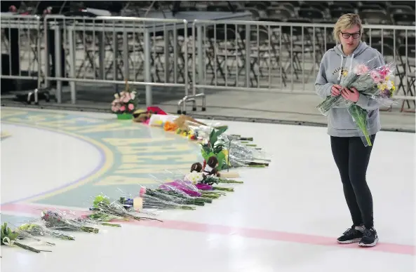  ?? MICHELLE BERG ?? A woman places flowers at centre ice Sunday as preparatio­ns were underway for a vigil at Humboldt’s Elgar Petersen Arena following Friday’s deadly bus crash.