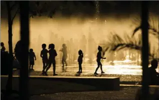  ?? THE ASSOCIATED PRESS FILE PHOTO ?? Children cool down in a fountain beside the Manzanares river in Madrid, Spain in this 2015 photo. Earth’s fever got worse last year, breaking dozens of climate records.