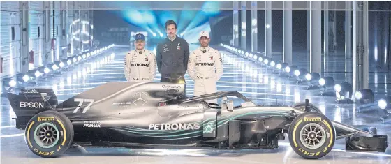  ??  ?? Mercedes drivers Valtteri Bottas, left, and Lewis Hamilton, right, and team chief Toto Wolff pose with the new car.