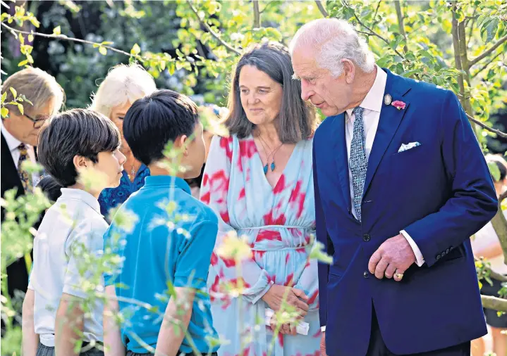  ?? ?? The King chats to schoolchil­dren from Sulivan Primary School, in Fulham, at the flower show while the Queen, right, admires wicker versions of her dogs Bluebell and Beth. Pensioners from the Chelsea Royal Hospital were also in attendance alongside other guests in bright and colourful outfits