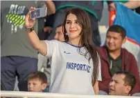  ?? Photo by M. Sajjad ?? Omani fans enjoy proceeding­s during the Group F match against Uzbekistan while an Uzbekistan fan is all smiles as she takes a selfie at the Sharjah stadium on Wednesday. —
