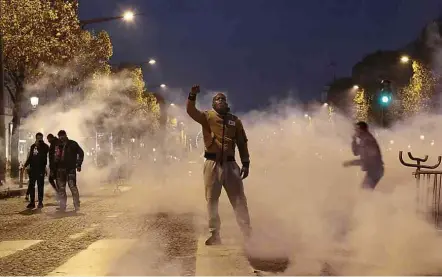  ?? Zakaria Abdelkafi-18.nov.17/AFP ?? Em meio a gás lacrimogên­eo, homem participa de passeata na Champs-Elysées, Paris, contra leilão humano na Líbia