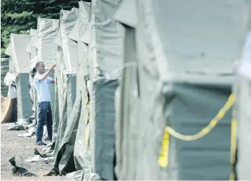  ?? PAUL CHIASSON / THE CANADIAN PRESS ?? An asylum seeker readjusts his tent in a temporary camp near Saint-Bernard-de-Lacolle, Que., earlier this month. The camp was set up to cope with the crush of asylum seekers crossing into Canada from the United States.