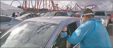  ?? (File Photo/AP/Jae C. Hong) ?? Licensed vocational nurse Joselito Florendo (right) administer­s the covid-19 vaccine to Michael Chesler at a mass vaccinatio­n site set up in the parking lot of Six Flags Magic Mountain in Valencia, Calif., on Jan. 22.