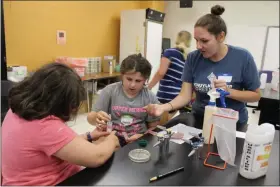  ?? PHOTO COURTESY OF SCHUYLKILL RIVER GREENWAYS ?? Schuylkill River Greenways education coordinato­r Sarah Crothers, standing, assist two girls with river sample testing at the Montgomery County Community College west campus during the H2YO! Summer Camp. The week-long camp teaches a group of middle school girls about the Schuylkill River Watershed through hands on experience­s such as water quality testing.