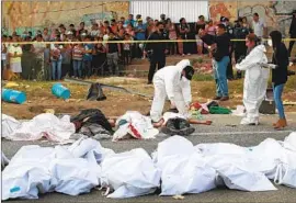  ?? Associated Press ?? OFFICIALS LAY out the bodies of the victims in Tuxtla Gutiérrez, Mexico. The tractor-trailer hit a curve and f lipped into the base of a bridge, authoritie­s said.