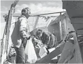  ?? QUENTIN WINSTINE/THE JONESBORO SUN ?? Stephanie Fatheree, right, salvages items from her tornado-damaged house Thursday in Harrisburg, Arkansas.