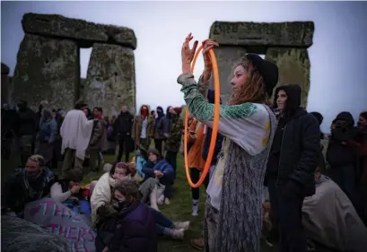  ?? AP ?? DEDICATED: People gather inside the stone circle at Stonehenge, where people jumped over the fence to watch the sun rise at dawn of the longest day of the year in the UK, in Amesbury, England, Monday.